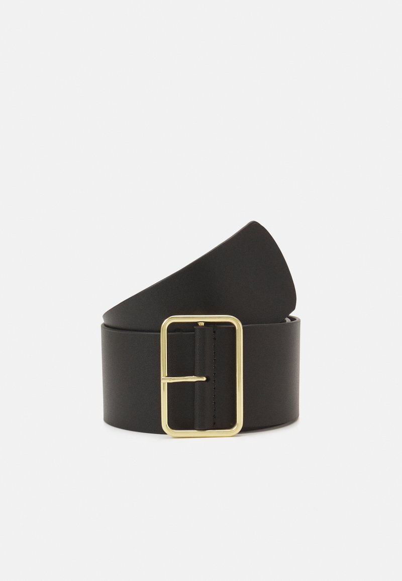 Ceinture large en cuir noir enroulée avec une grande boucle rectangulaire en métal doré sur un fond clair uni.