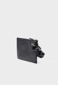 Czarna skórzana kopertówka z zamkiem błyskawicznym. Posiada marszczony uchwyt, który stanowi teksturowany akcent w gładkim, minimalistycznym designie.