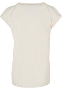 Lichtbeige t-shirt met een ronde halslijn, korte omgeslagen mouwen, en een zachte, gladde textuur. Eenvoudig ontwerp zonder zichtbare patronen of accenten.