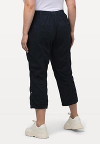 Marina capribyxor med elastisk midja, två bakfickor och en avslappnad passform, tillsammans med vita chunky sneakers.