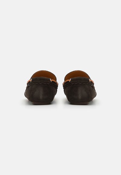 Mocassins en suède marron foncé avec des bords festonnés, des détails en métal près du talon et une texture lisse. Pas de lacets visibles.