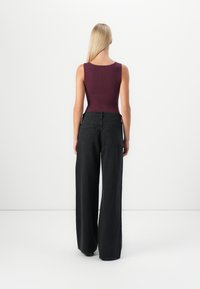 Black wide-leg jeans paired with a maroon fitted tank top. Features a ribbed texture and standard back pockets. Smooth fabric; no visible patterns.