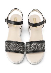 Sandali in pelle nera con suola piatta e cinturino alla caviglia regolabile. Il cinturino largo è decorato con dettagli in glitter neri e argento.