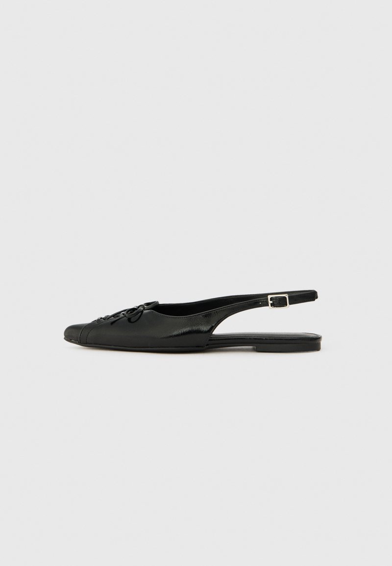 Black leather slingback shoe with a rounded toe, decorative bow detail, flat heel, and adjustable buckle strap. Smooth texture, minimalistic design.