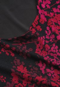 Zwarte stof met een bloemenpatroon in tinten van roze en rood. De textuur is glad en toont ingewikkelde bloemendetails.