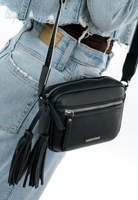 Borsa a tracolla in pelle nera con finitura texture, dotata di tasche con zip e frange decorative. Tracolla regolabile per un trasporto comodo.