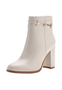 Beige ankelboot med en slät lädertextur, med hög blockklack, dragkedjestängning och dekorativ rem med metalliska accenter.