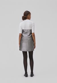 Hvid kortærmet top parret med en metallisk sølvnederdel. Outfittet har en struktureret pasform med en glat tekstur og en subtil glans.