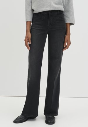 Zwarte denim flared jeans met een gladde structuur, vijf zakken en contrasterende stiksels. Draag het met een lichtgrijs vest en zwarte schoenen.