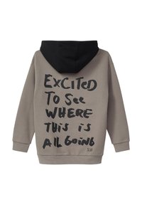 Szara bluza z kapturem, z czarnym kapturem, z dużym czarnym ręcznie napisanym tekstem "Podekscytowany, aby zobaczyć, dokąd to wszystko zmierza" na plecach.