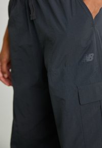 Schwarze Sportshorts mit elastischem Bund, ausgestattet mit einer Seitentasche und einem dezenten Logo. Gefertigt aus leichtem, strukturiertem Stoff.