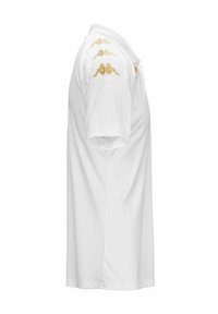 Witte polo met korte mouwen, met gouden logo's op de schouders, gemaakt van lichte stof met een klassieke kraag en een rechte onderrand.