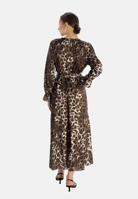 Robe maxi avec un imprimé léopard marron et beige, des manches longues, une ceinture à nouer à la taille, et un tissu fluide et doux.