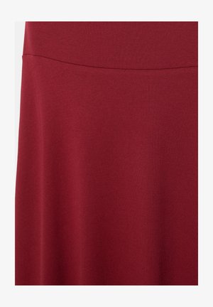 Syvänpunainen kangas, jossa on sileä rakenne ja vaakasuora sauma lähellä yläosaa.