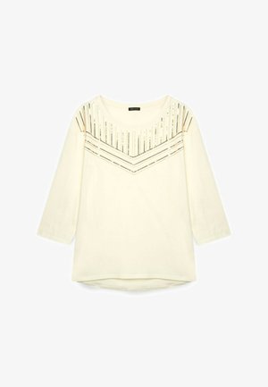 Top color crema con scollo a barca e maniche a tre quarti, caratterizzato da perline metalliche decorative disposte in un motivo a forma di V sulla parte anteriore.