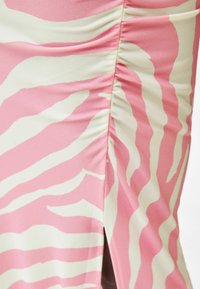 Rosa Kleid mit einem subtilen Zebra-Streifenmuster in Creme. Verfügt über seitliche Raffung und einen Seitenschlitz, hergestellt aus einem glatten, leichten Stoff.
