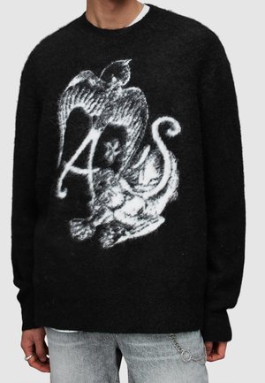 Zwarte pluche trui met wit abstract ontwerp dat een vogel, een krullende staart en de letters "A" en "S" combineert aan de voorkant.