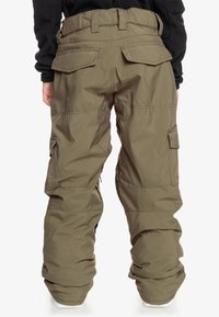 Pantalons style cargo en vert olive, avec une taille haute, plusieurs poches, une coupe décontractée et une texture lisse. Sangles réglables à la taille.