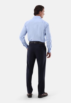 Hellblaues kariertes Hemd mit langen Ärmeln, kombiniert mit dunkelblauen Hosen und braunen Schuhen. Rückansicht zeigt Kragen- und Nähte-Details.