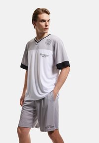 Conjunto deportivo para hombres que incluye una camiseta de manga corta en gris y blanco con detalles en negro y pantalones cortos grises a juego, fabricados con tejido ligero.