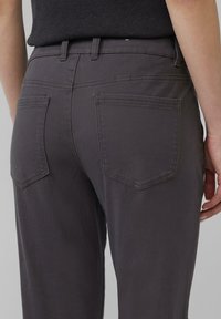 Donkergrijze katoenen broek met een slim fit, subtiele textuur en twee achterzakken met schuine randen. Zichtbare tailleband met riemlussen.