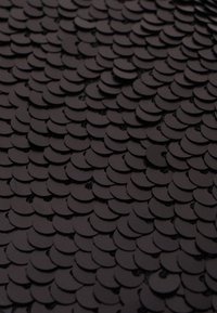 Black sequin fabric featuring overlapping circular shapes, creating a textured, scale-like appearance across the surface.