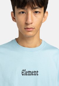 Light blue cotton t-shirt with short sleeves, featuring black text "Element" in a bold font across the front.