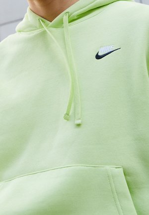 Jasnozielona bluza z kapturem z haftowanym na piersi logo Nike w białym i czarnym kolorze, z sznurkami i przednią kieszenią.