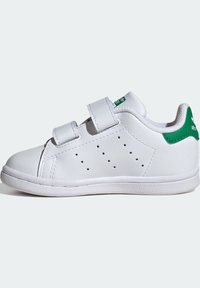 Białe niskie sneakersy z zielonym paskiem na pięcie, perforowanymi detalami po bokach oraz dwoma szerokimi paskami na rzepy.