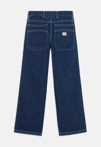 Mørkeblå denim bukser med vide ben, har høy midje, to baklommer og kontraststing. Ingen dekorasjoner.
