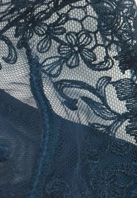 Marinblå spets med blommönster och vinrankor; delikat, öppen nätstruktur; intrikata sömmar framhäver detaljerade designelement.