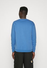 Blå sweatshirt gjord av mjukt material, med rund halsringning och ribbade muddar. Slät textur med en subtil glans. Casual passform.