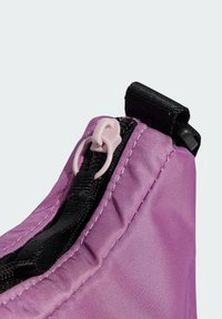 Funda de tela morada con superficie texturizada, que presenta un zipper negro y un tirador de zipper rosa. Forma redondeada con bordes cosidos.