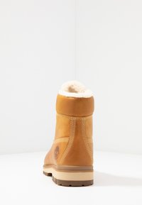 Braune Leder-Stiefelette mit einem plüschigen crème-farbenen Futter, geformter Gummisohle und kontrastierenden Nähten. Verfügt über ein geprägtes Logo an der Seite.