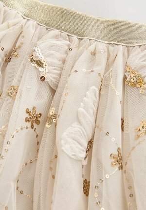 Krém színű tüll szoknya arany elasztikus derékpánttal, arany flitterekkel és virágos hímzéssel díszítve, texturált és rétegezett megjelenést kölcsönözve.
