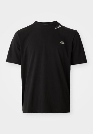 Juoda trumpos rankovės apvalios iškirptės marškinėliai su mažu žaliu krokodilo logotipu ant krūtinės ir balta rašyta "Lacoste" užrašu šalia apykaklės.