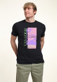 Camiseta negra de manga corta con un gráfico de Van Gogh en rosa y morado con texto verde. Material de algodón, diseño ajustado.