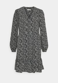 Mekko, jossa on musta-valkoinen kuvio, v-pääntie, pitkät puffihihat ja röyhelöhelma. Valmistettu kevyestä kankaasta, jolla on virtaava muoto.