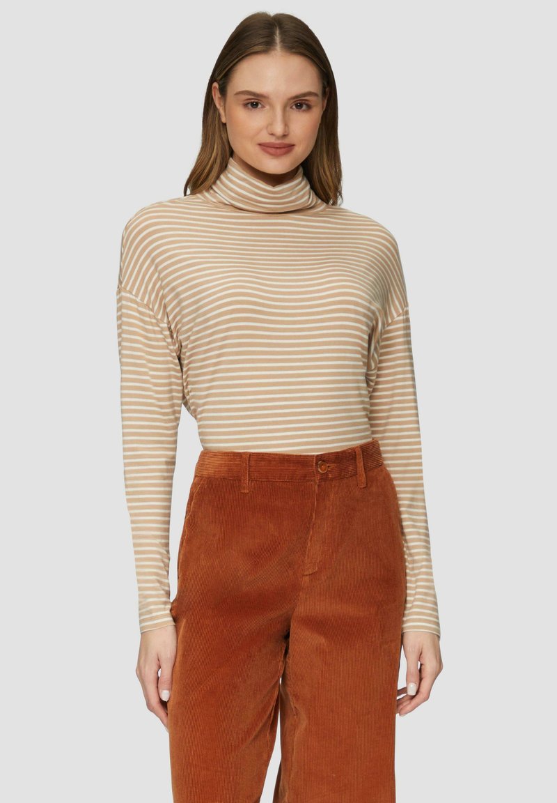 Gestreifter Rollkragenpullover in Beige und Creme mit langen Ärmeln. Kombiniert mit orangefarbenen Cordhosen, die über einen Knopf und Gürtelschlaufen verfügen.