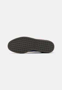 Gummisåle til sneakers med et teksturert gripe mønster i mørk grå. Rund form med lett buing ved tærne. Minimalistisk design.