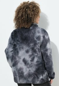 Pullover in fleece morbido e di peso medio, con un motivo tie-dye grigio e nero. Presenta un colletto alto e maniche lunghe, con una vestibilità rilassata.