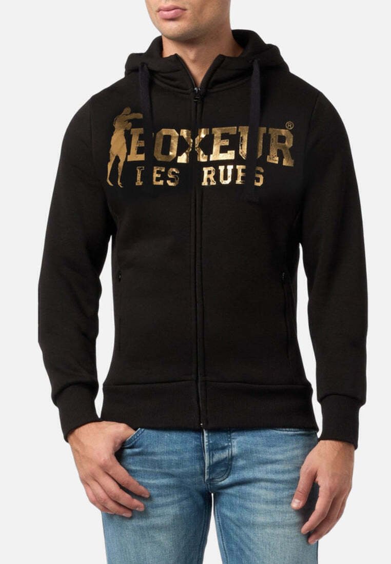 Felpa nera con zip, caratterizzata da un logo frontale in oro, cappuccio con cordino e tasche a marsupio. Il tessuto risulta morbido con una texture liscia.