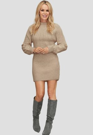 Beiges Strickkleid mit gerippter Textur, hoher Halslinie und langen Ärmeln. Kombiniert mit hohen grauen Wildlederstiefeln.