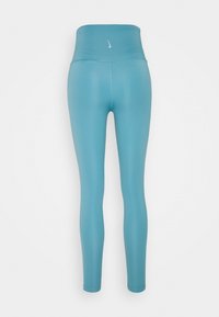 Modré legíny s vysokým pasem vyrobené z pružného materiálu, s hladkým povrchem a malým logem na pasu.