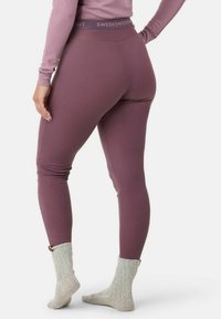 Ribbed legginsy w kolorze mauve z wysokim elastycznym pasem. Noszone z jasnoszarymi dzianinowymi skarpetkami. Prosty, dopasowany fason bez dodatkowych wzorów.