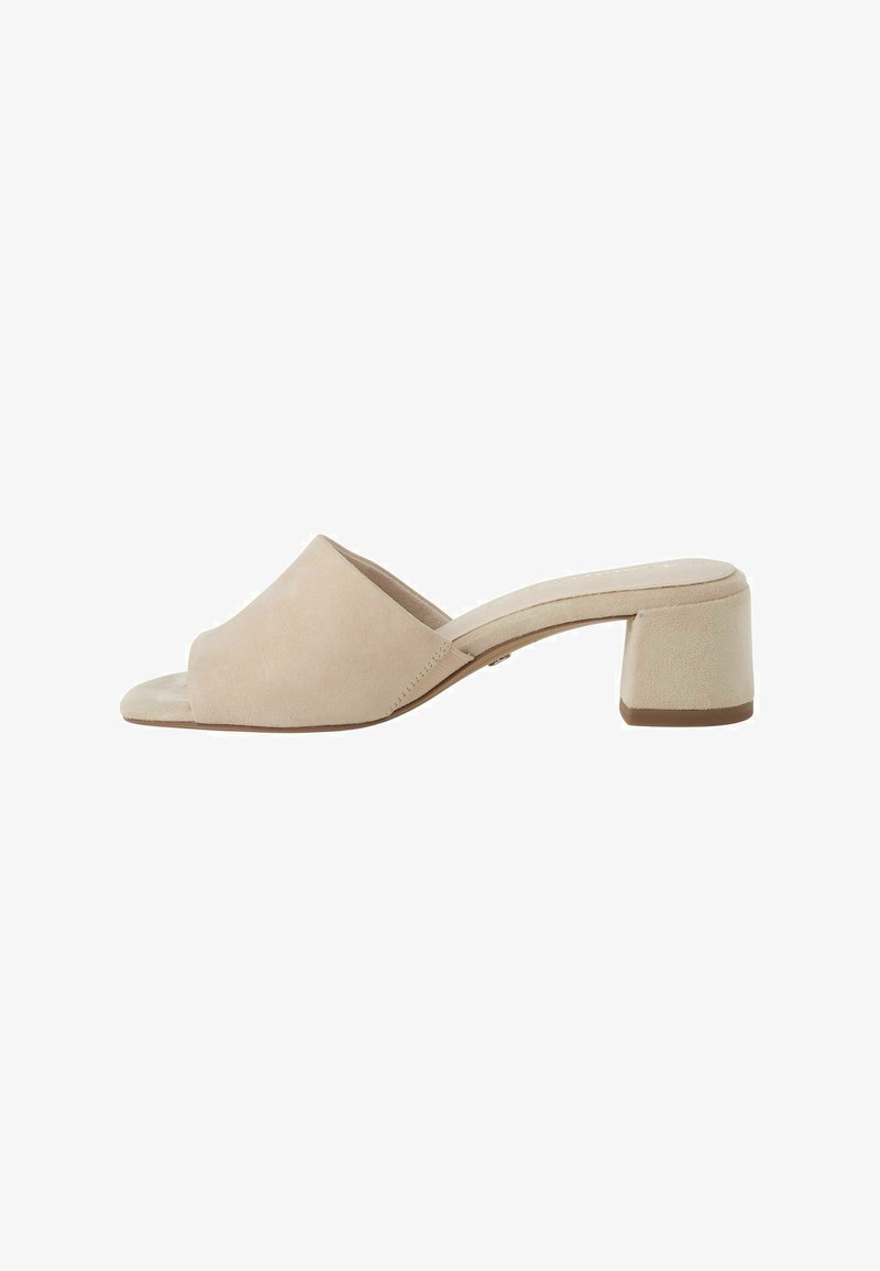 Mule en daim beige à bout ouvert avec un petit talon carré et un design à enfiler, présenté de profil sur un fond blanc.