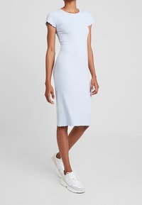 Vaaleansininen ribbikuvioinen midi-mekko, jossa on lyhyet aaltojyrkkähihojen ja suora kiilto, joka sisältää repsottavan helman. Yhdistettynä valkoisiin urheilukenkiin.