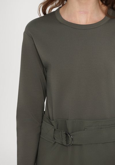 Top lungo a maniche, color verde khaki, con scollatura tonda e cintura in tessuto con fibbia in metallo nera, realizzato in un materiale leggero e morbido.