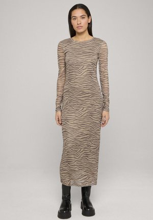 Tan long-sleeve dress with a zebra stripe pattern, made of sheer fabric. It has a crew neckline and is paired with black ankle boots.
