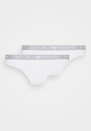 White cotton thongs with a grey elastic waistband featuring "EMPORIO ARMANI" logo repeated. Smooth texture; minimal design. Pack of two.